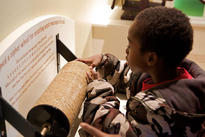 A boy operates a large-scale model of Jefferson's Wheel Cipher