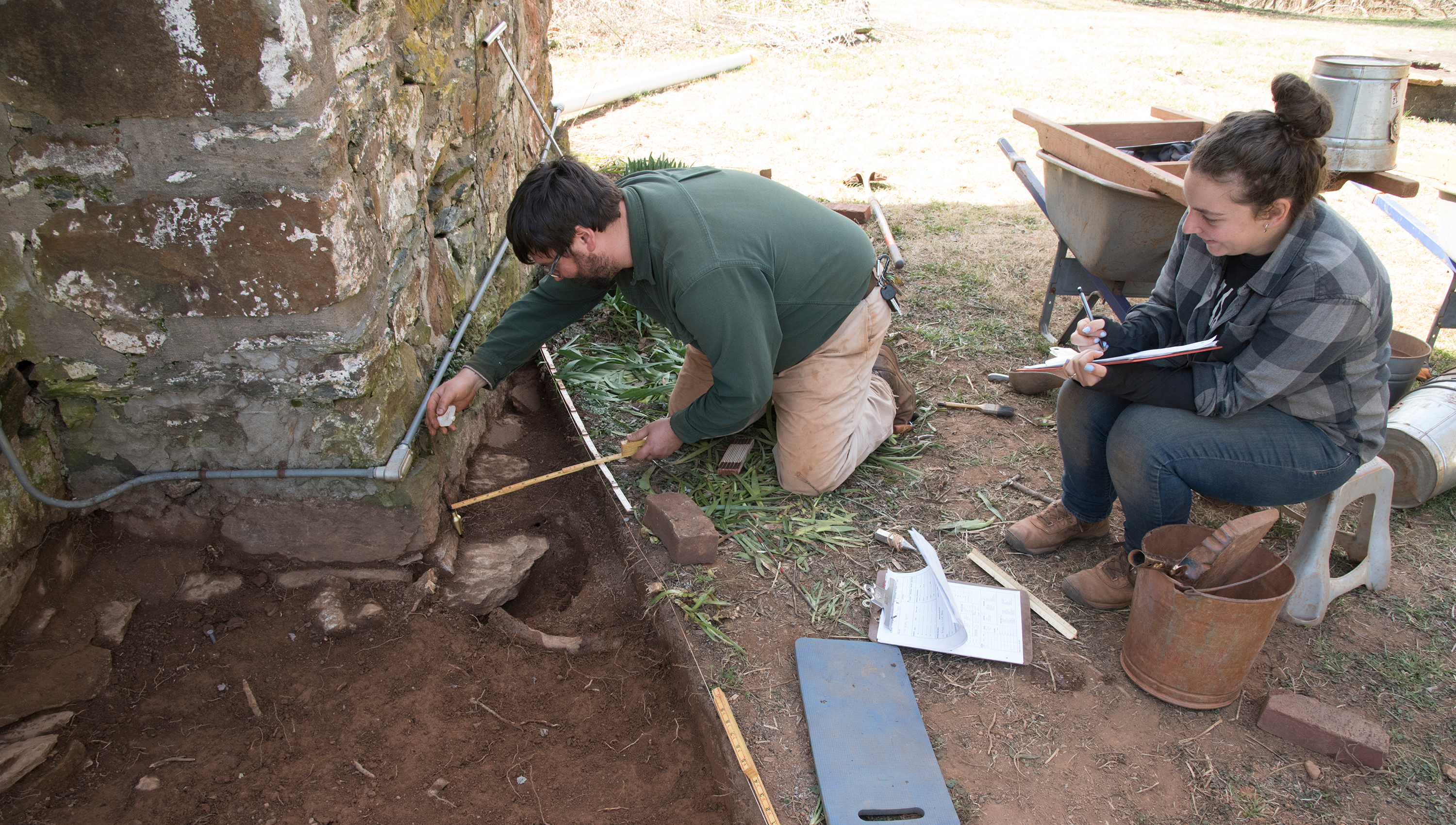 Archaeologists Craig Kelley and Sarah Corkett continue to measure and map the foundation footer of the Stone House